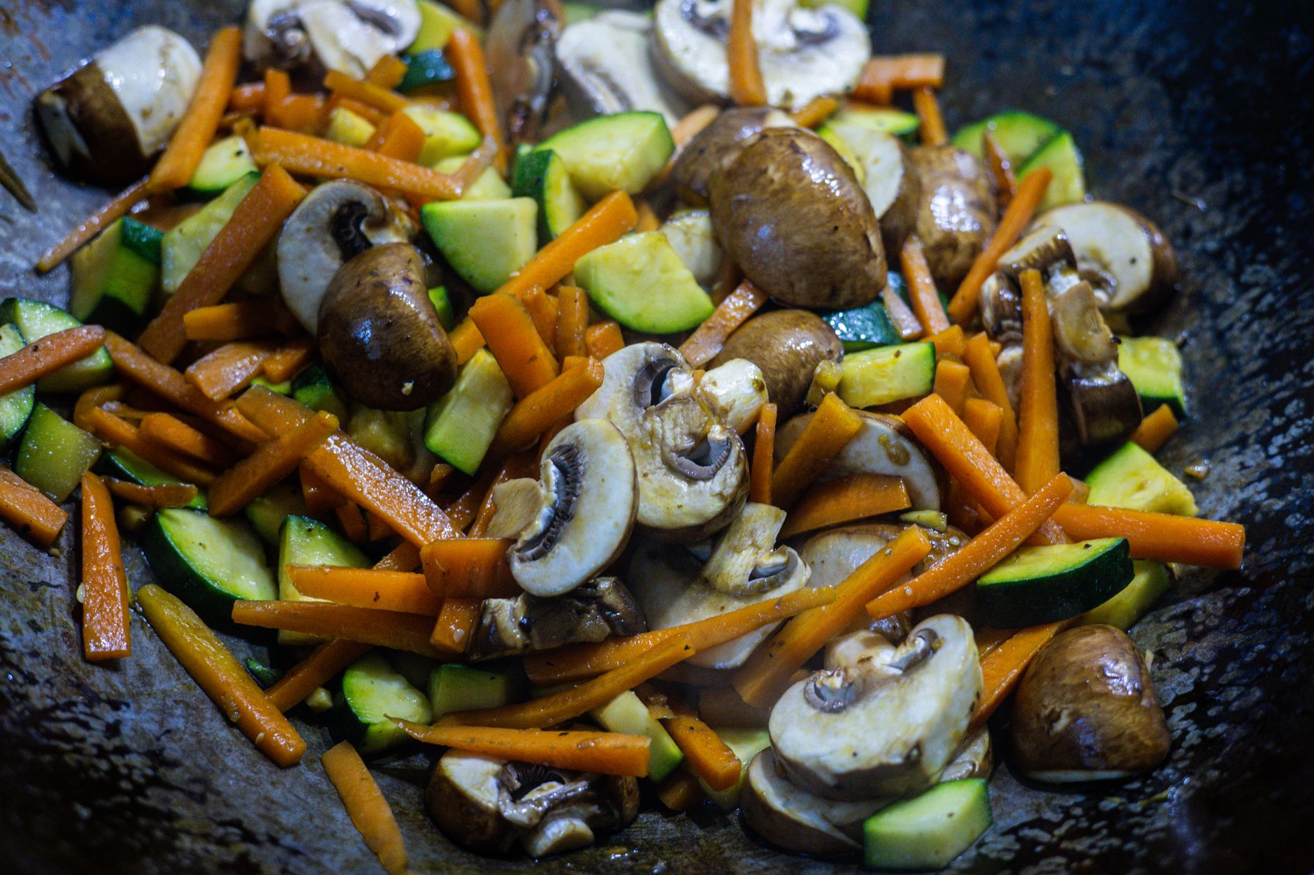 Vegetable stir fry with mushrooms, carrots and zucchini cooking in a wok