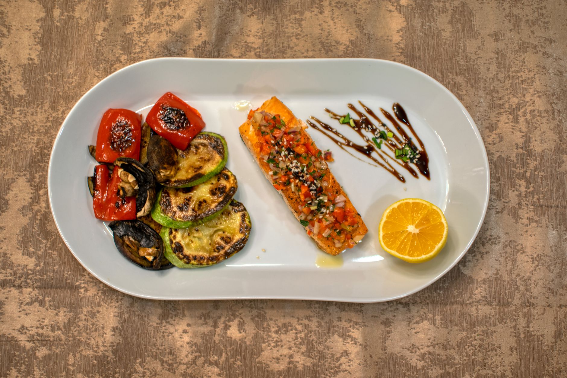 Plate of grilled salmon with roasted vegetables and lemon