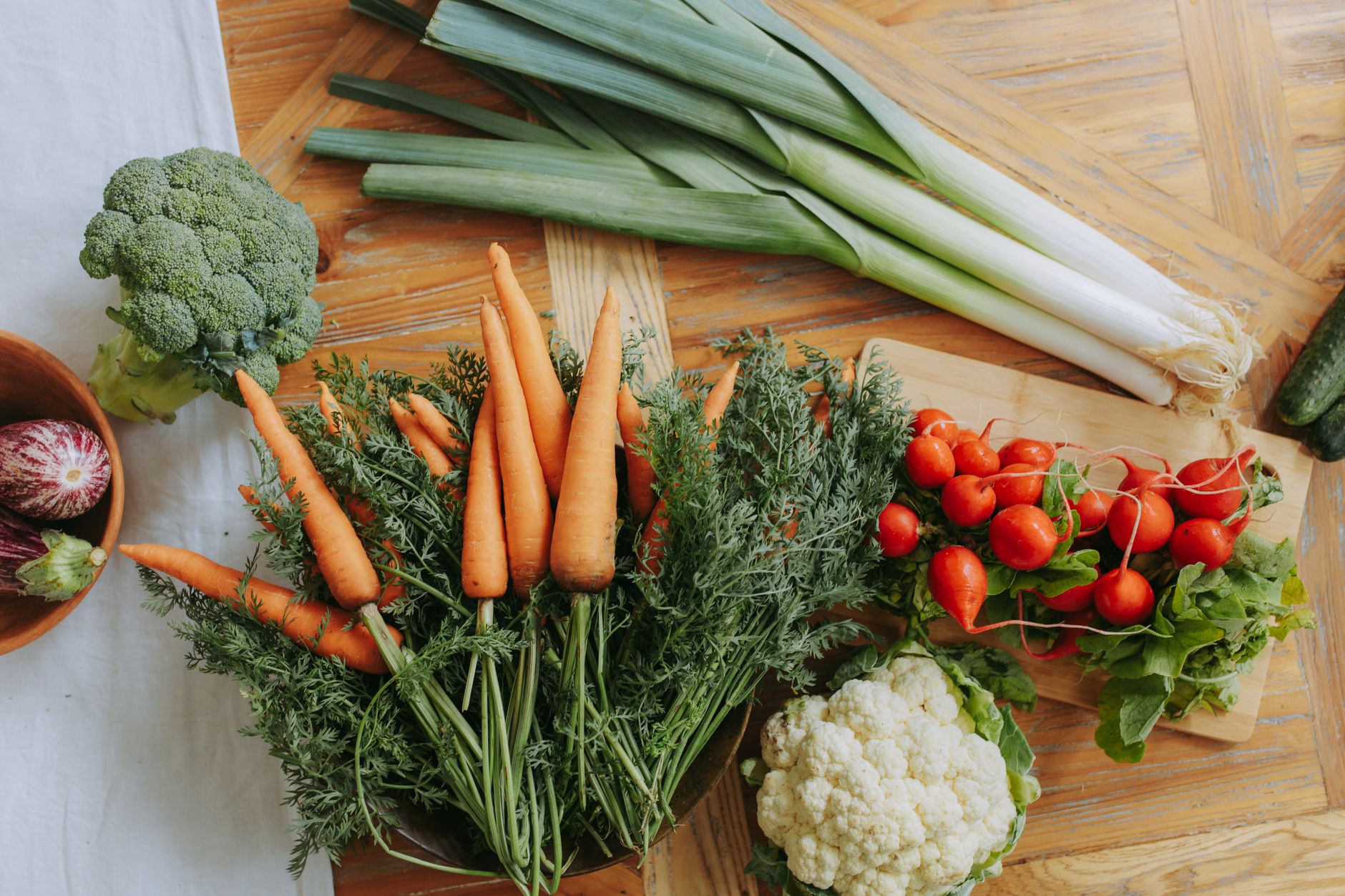 Fresh vegetables including carrots, broccoli, cauliflower and radishes on a wooden table