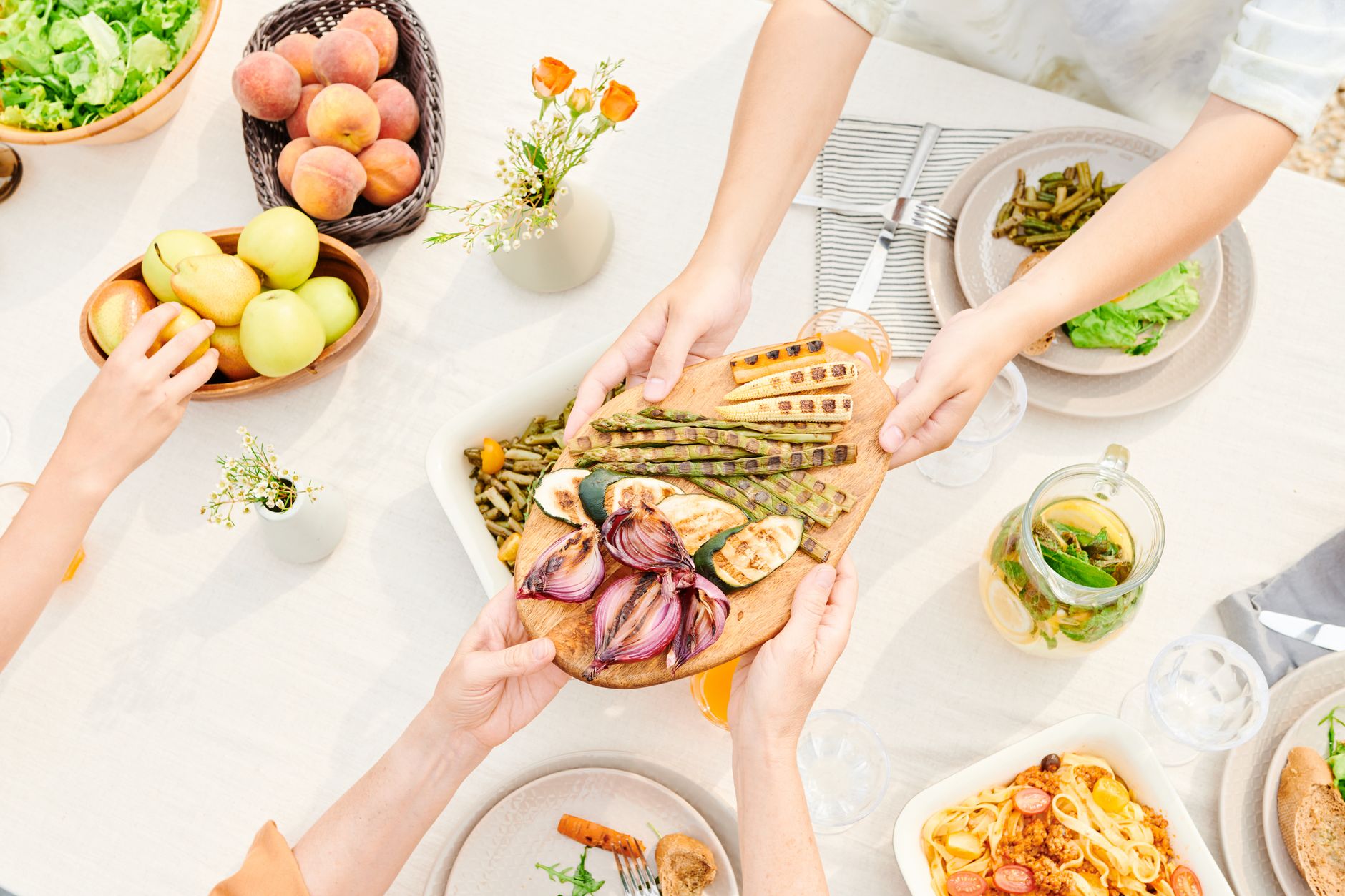 Family passing a platter of grilled vegetables at the dinner table