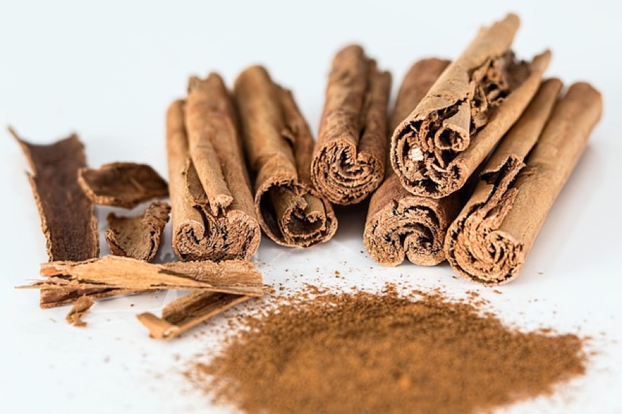 Cinnamon sticks, bark pieces and a pile of ground cinnamon on a white background
