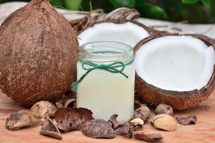 Jar of virgin coconut oil next to a whole coconut and a halved coconut