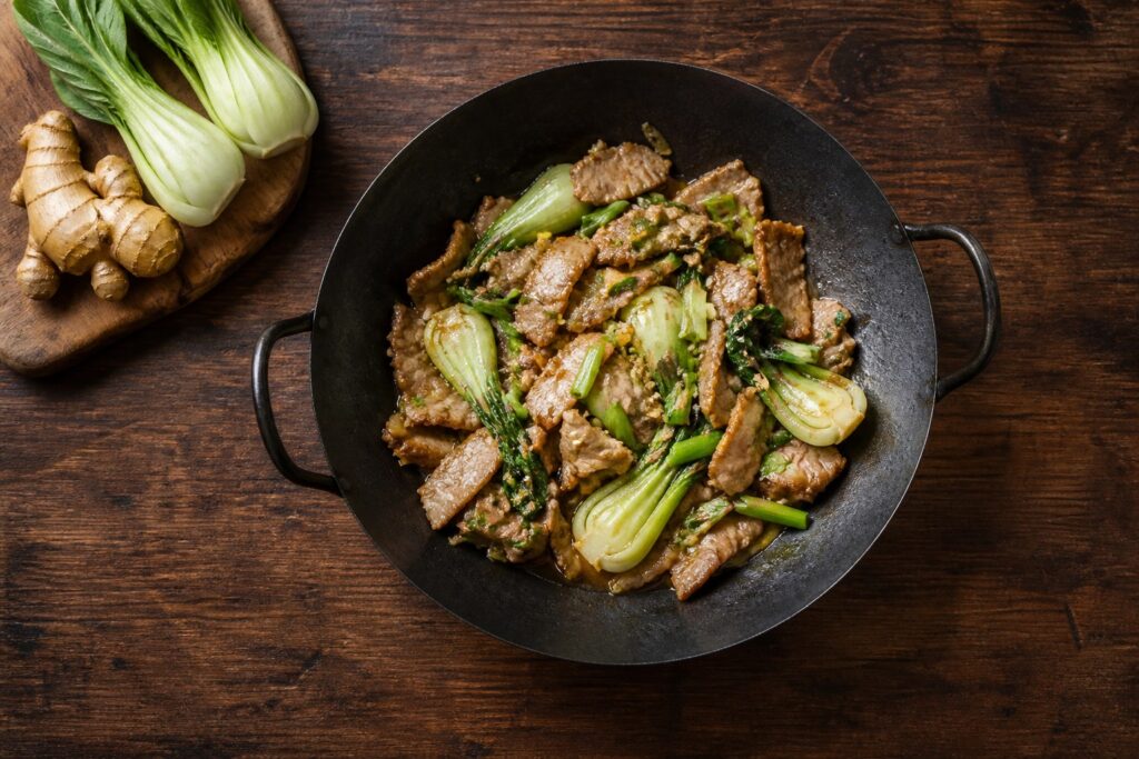 AIP ginger pork stir-fry with baby bok choy and spring onion in a carbon steel wok