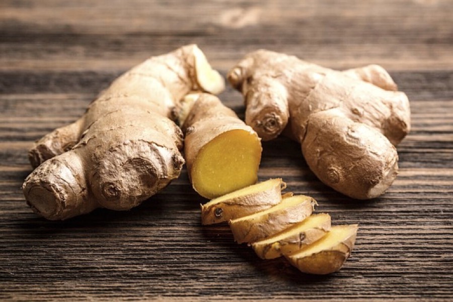 Fresh ginger root, whole and sliced, on a wooden board