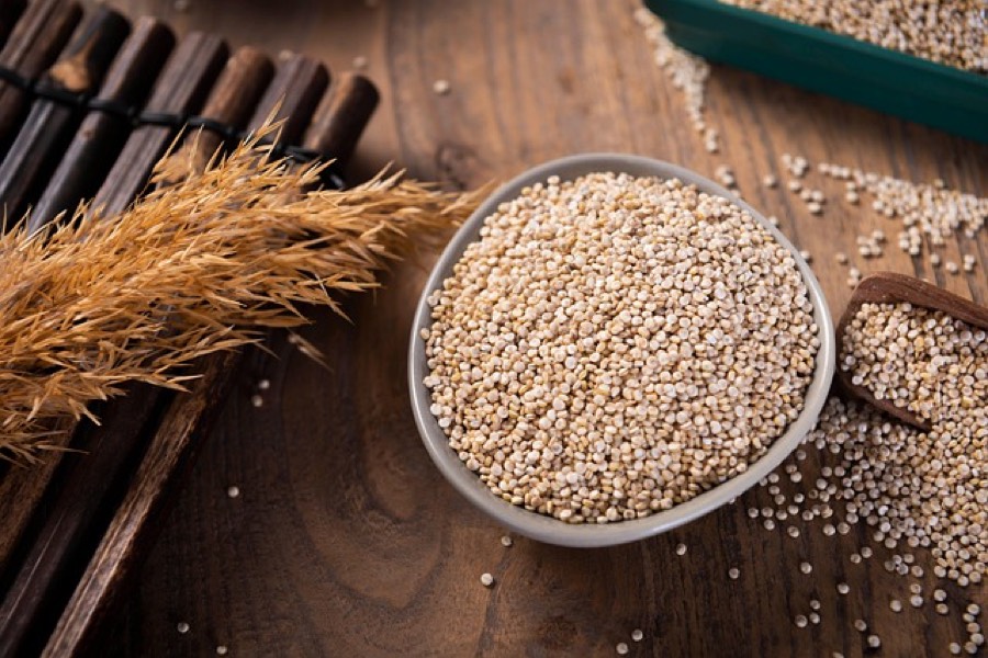 Raw white quinoa seeds in a small bowl on a wooden table