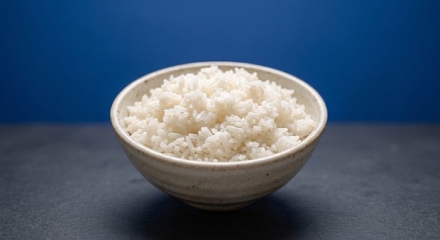 Bowl of plain cooked white rice on a dark surface