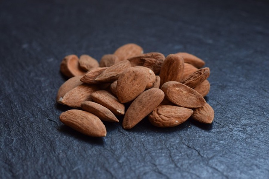 Raw whole almonds with their brown skins on a dark slate surface
