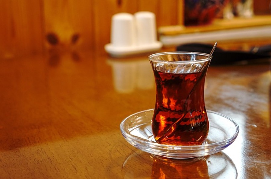 Glass cup of freshly brewed black tea on a saucer
