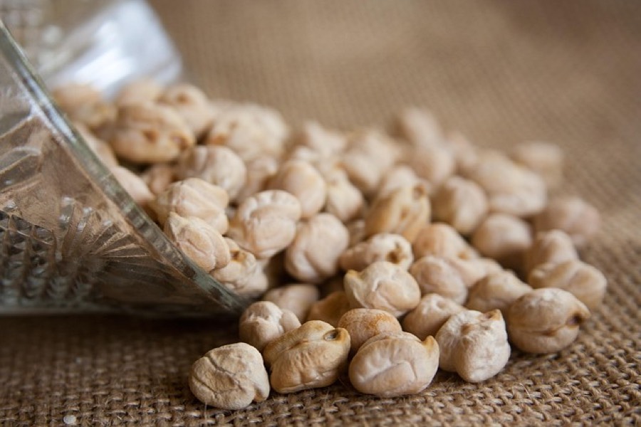 Dried chickpeas spilling from a glass bowl onto a burlap cloth