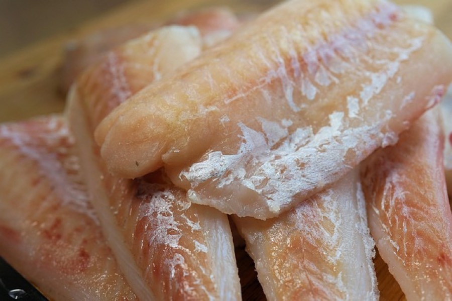 Raw cod loins stacked on a wooden board