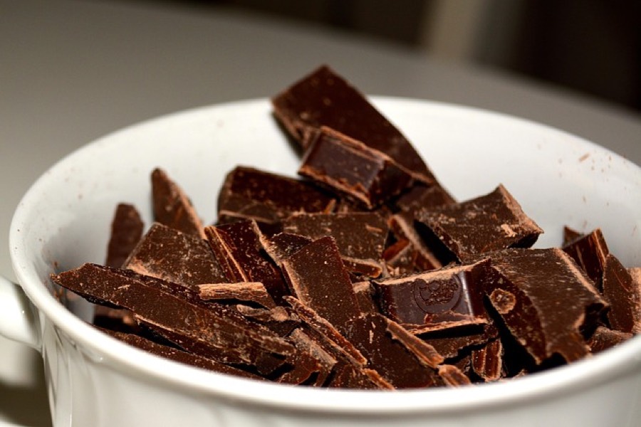Broken pieces of dark chocolate in a white bowl