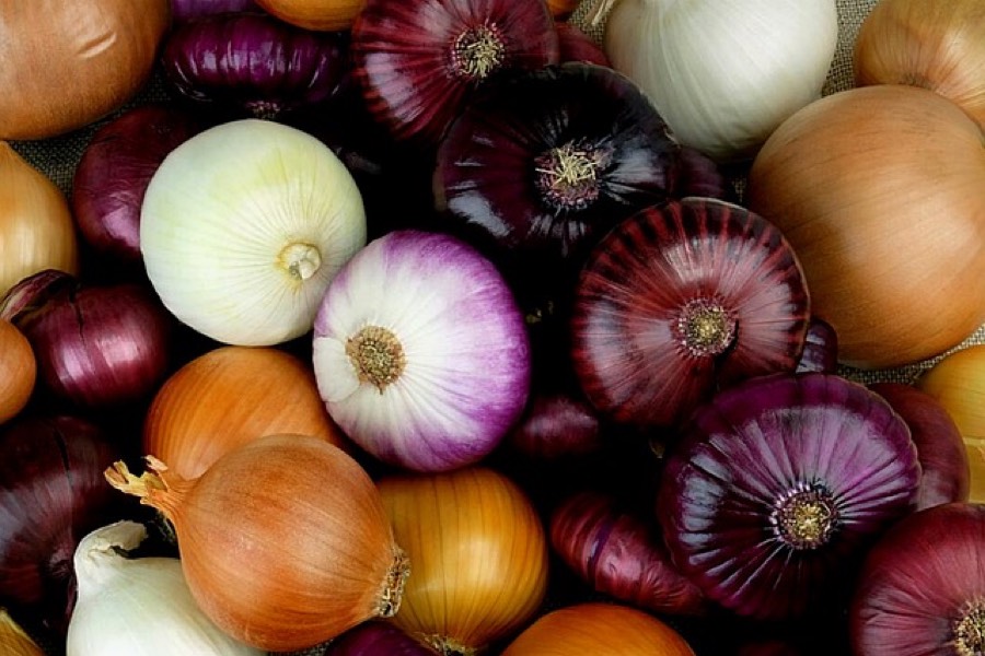 Yellow, white and red onions piled together, whole and unpeeled