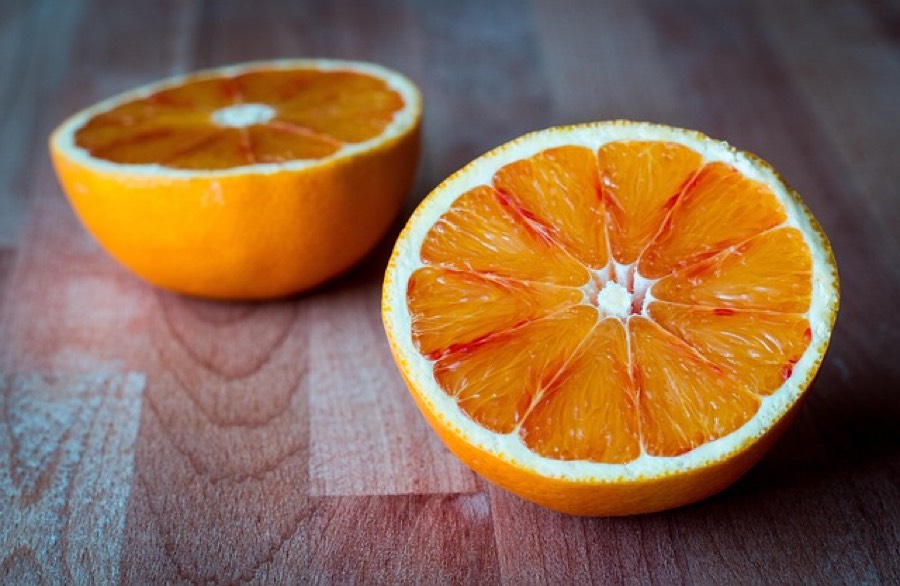 Two halves of a fresh orange on a wooden board, showing the segments and the white pith