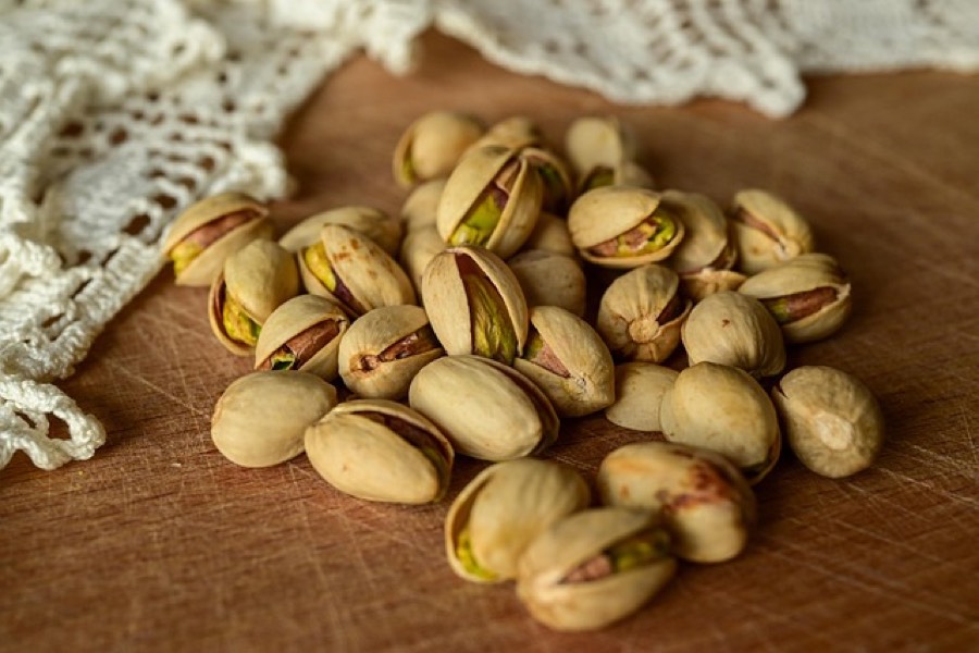 Pistachios in the shell split open, showing the green kernel and thin purple skin