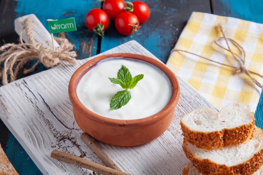 A bowl of thick plain Greek yogurt on a wooden board