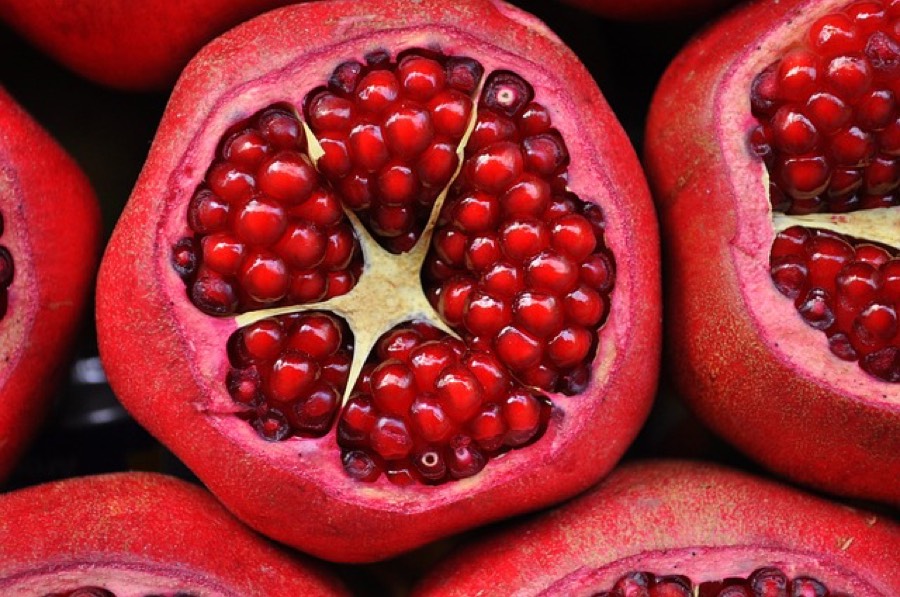 Ripe pomegranates cut open showing clusters of red arils