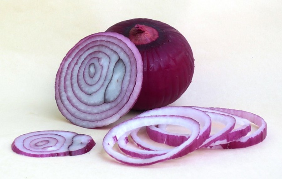 Whole red onion next to a halved bulb and loose red onion rings
