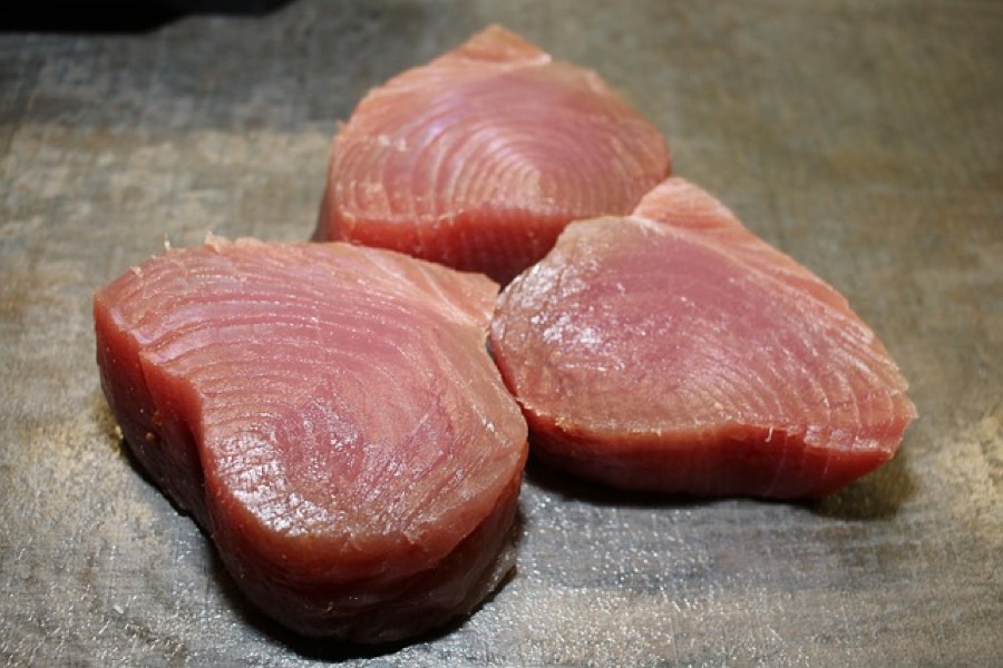 Three raw tuna steaks on a stone surface