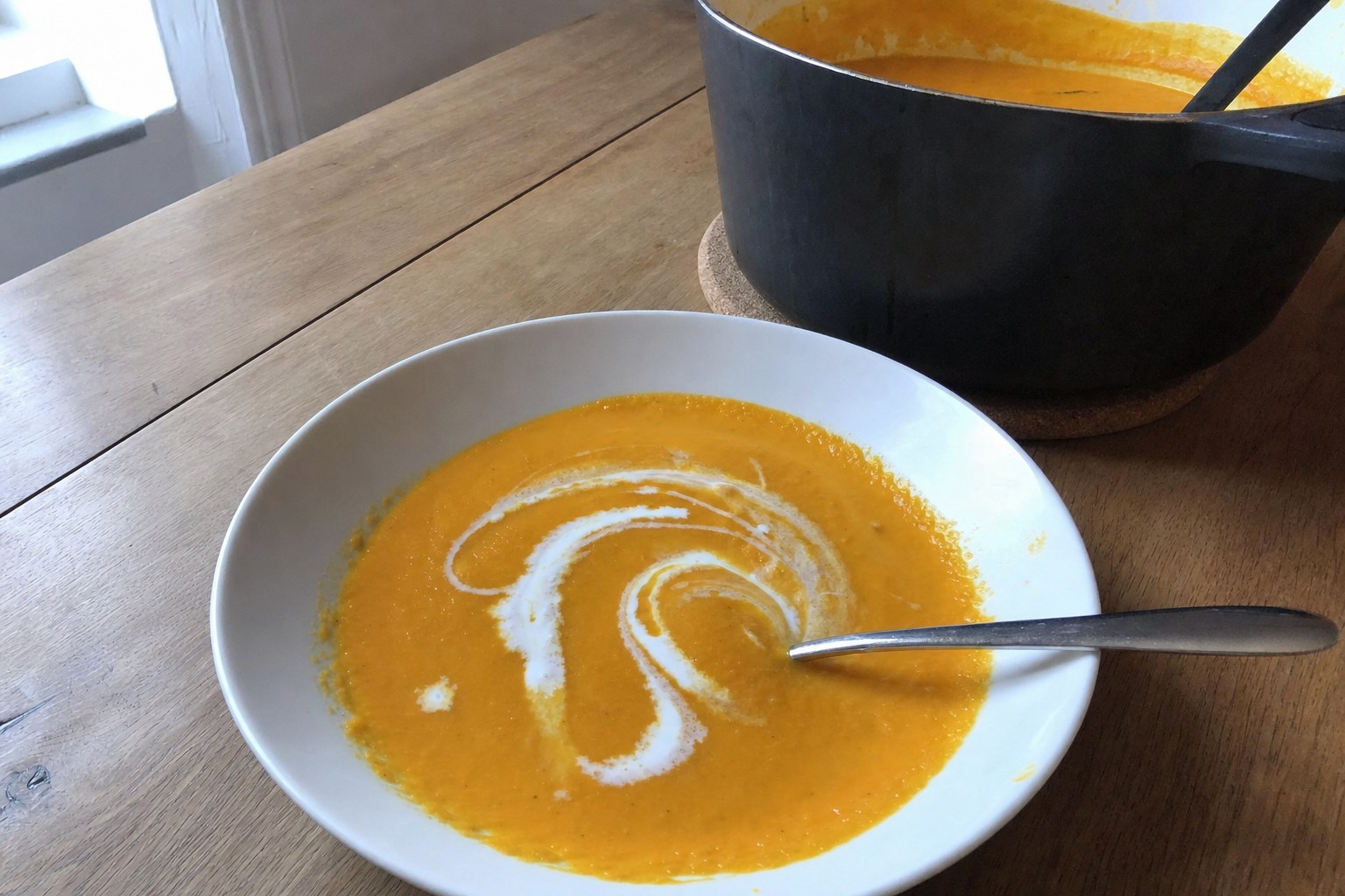 AIP creamy carrot ginger soup with a coconut milk swirl and fresh ginger in a ceramic bowl