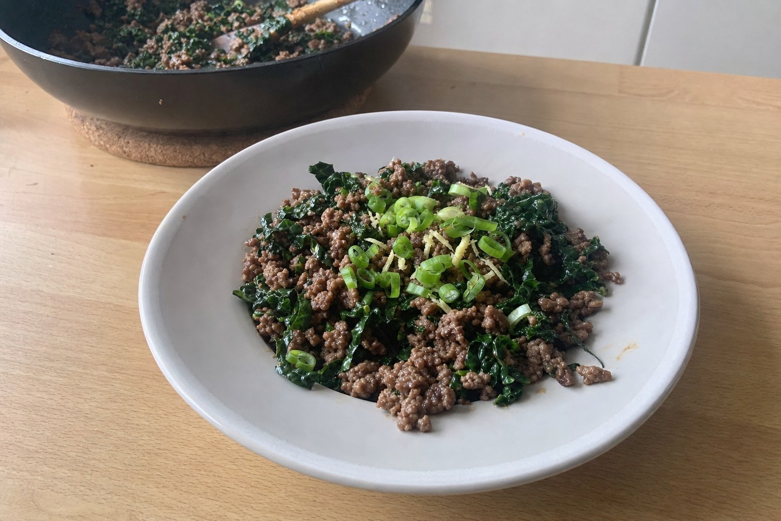 AIP ginger beef and kale breakfast skillet with spring onions in a cast iron pan