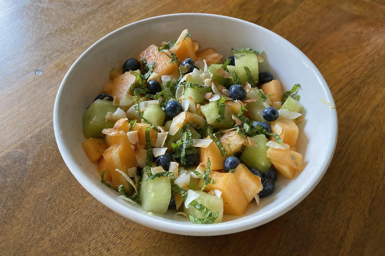 AIP melon and mint breakfast bowl with cantaloupe, honeydew, blueberries and toasted coconut flakes