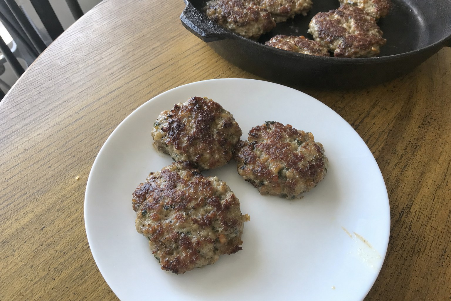 AIP pork and apple breakfast sausage patties with fresh sage in a cast iron skillet